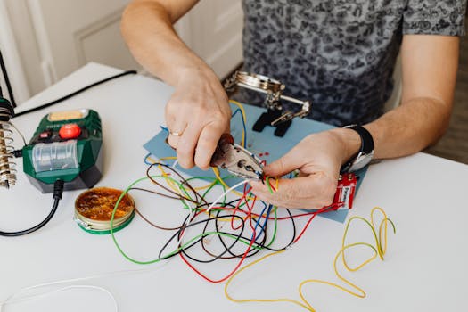 A technician precisely cuts and organizes colorful wires using pliers, showcasing expertise in wiring tasks.
