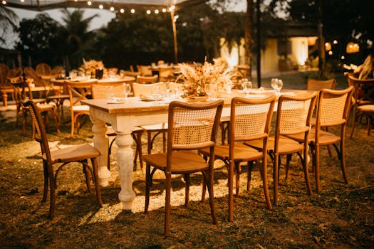 Beautifully arranged outdoor wedding reception tables under warm evening lights.